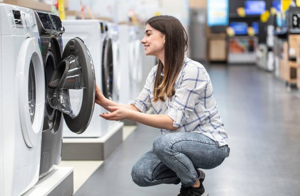 a young woman in a store chooses a washing machine.. the concept of shopping.